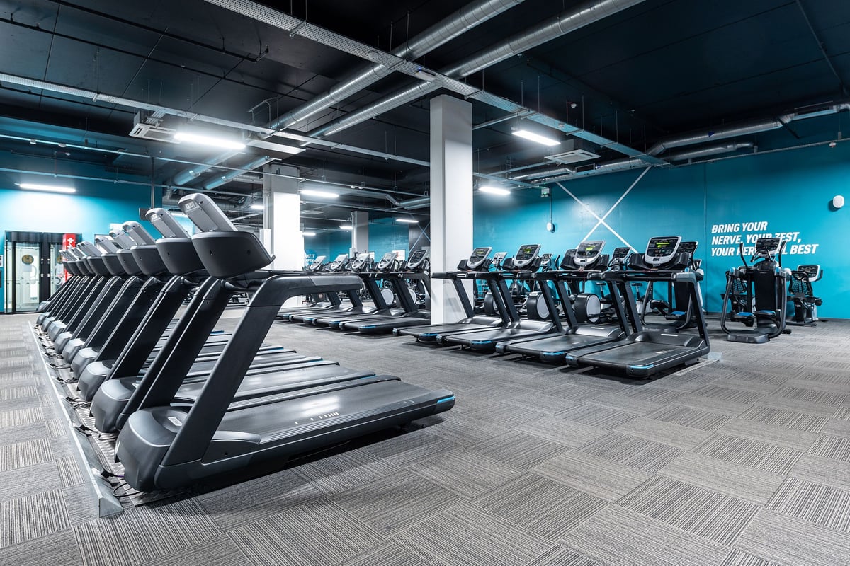 PureGym Norwich Castle Mall: Rows of treadmills and ellipticals in a modern gym with blue accent lighting.
