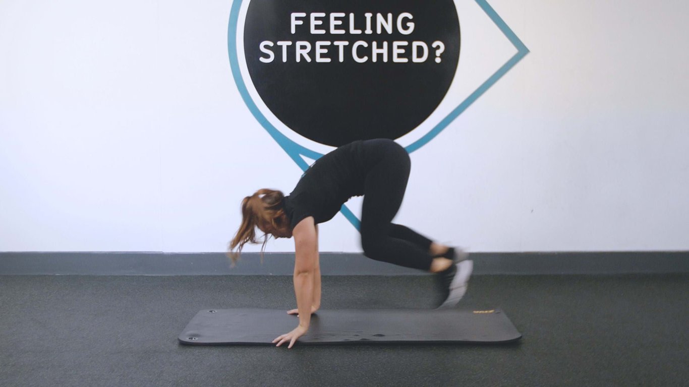 Woman in black workout clothes doing mountain climber exercise on mat indoors