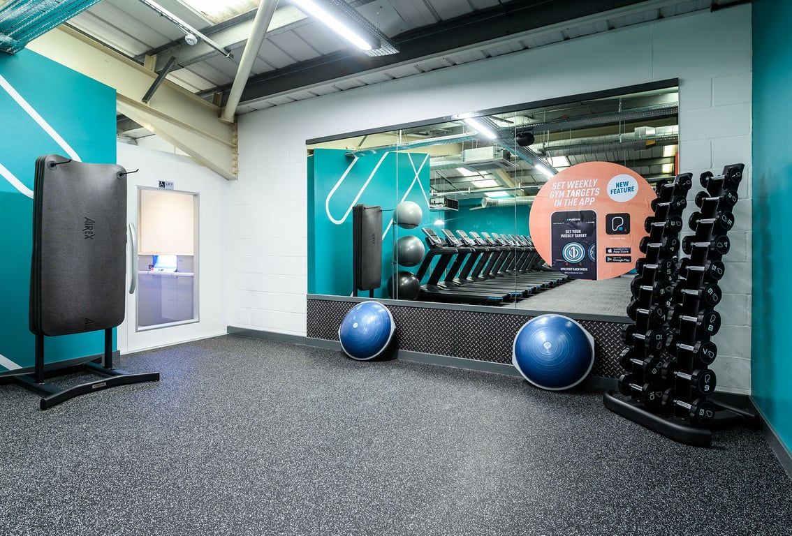 PureGym Burgess Hill: Resistance machines, exercise balls, rubberized flooring in a teal and grey fitness studio.