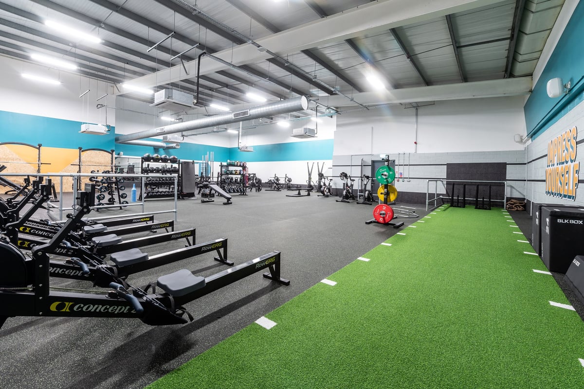 PureGym Loughborough: Free weights, turf area, resistance machines, mirrors, and rubberized flooring in a gym interior space.