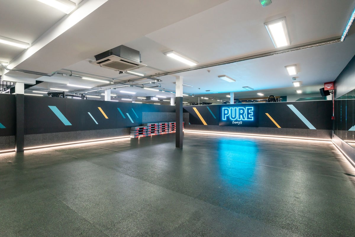 PureGym Wrexham: Futuristic studio interior with neon-lit walls and stacks of class equipment.