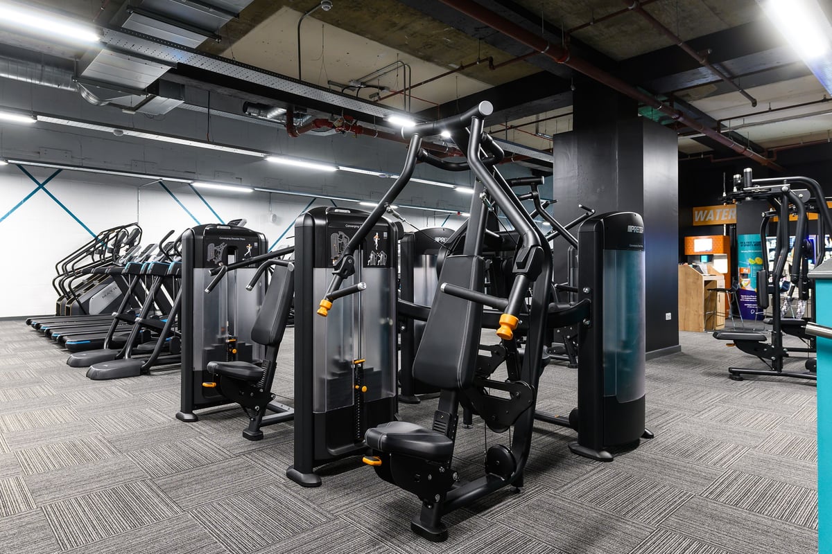 PureGym Hemel Hempstead: Rows of resistance machines, benches, and weight stacks in a dimly lit gym space.