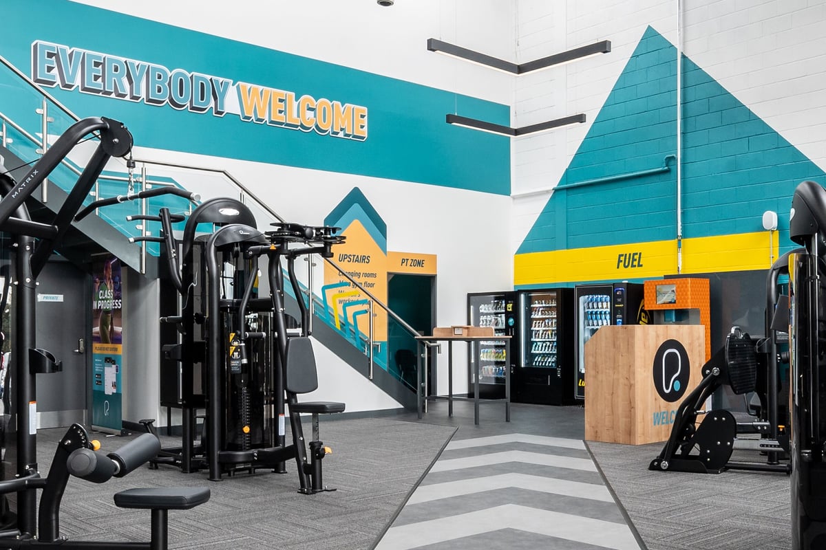 PureGym Dewsbury: Resistance machines, free weights, benches, and teal-colored gym equipment in a welcoming space.