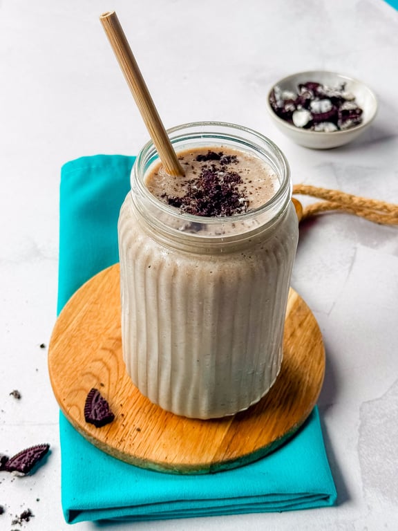 Milkshake with crushed chocolate cookies in a ribbed glass jar with a bamboo straw