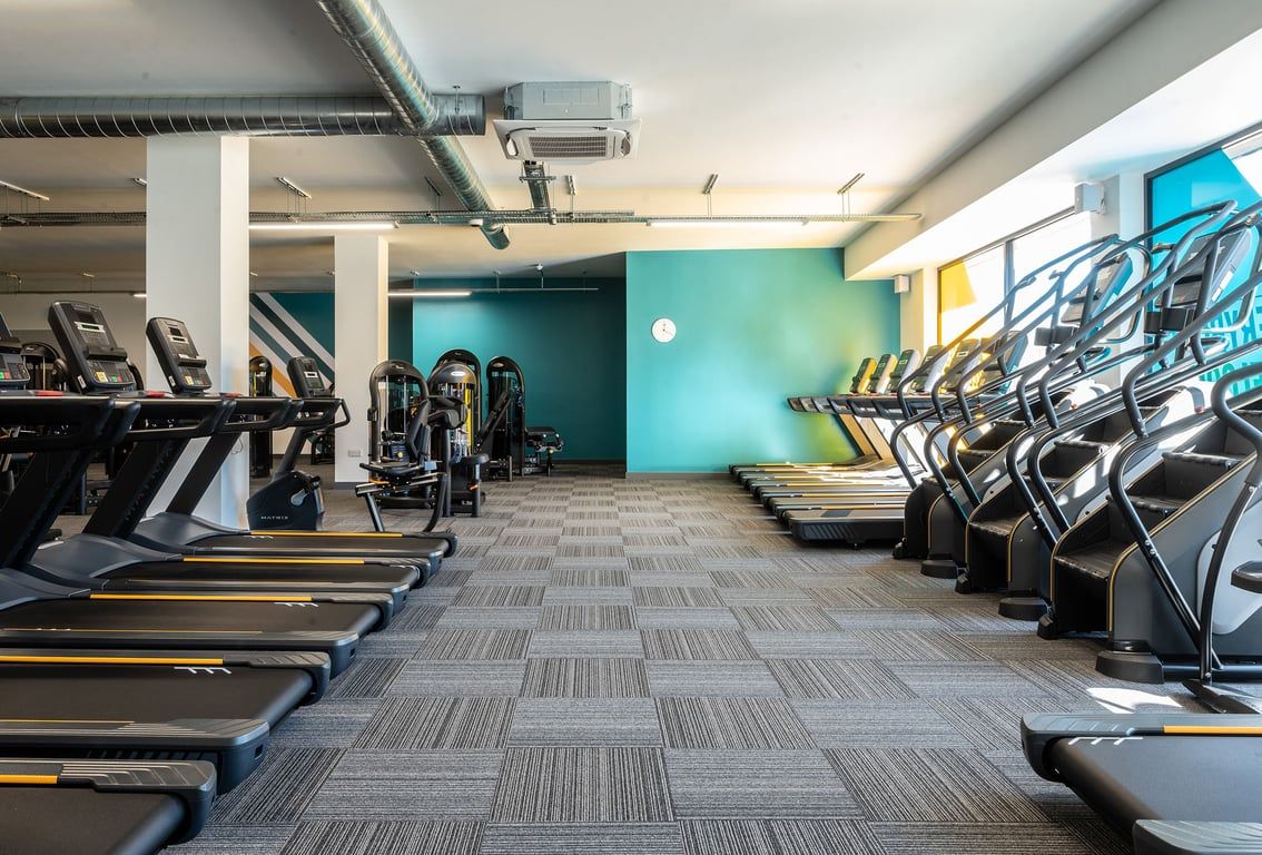 PureGym London Catford Rushey Green: Rows of treadmills, ellipticals, exercise bikes, and wall graffiti art.