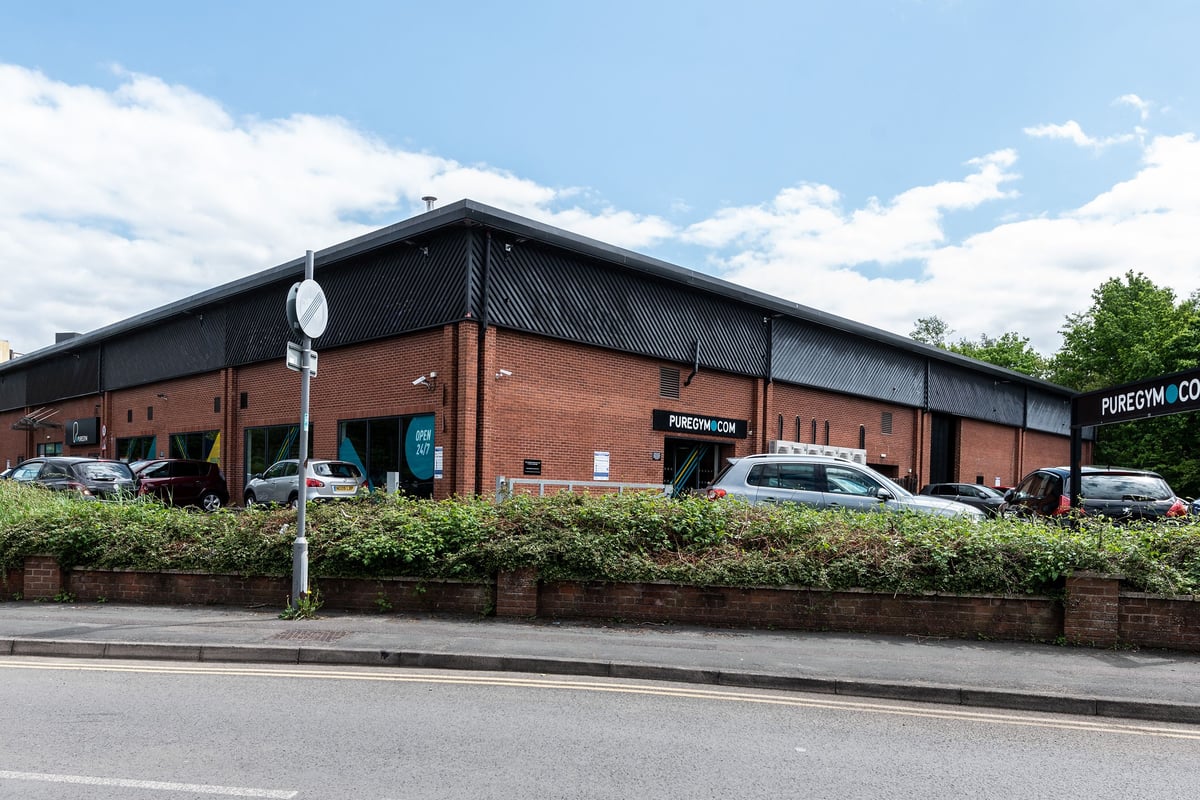 PureGym Woking: Exterior of a fitness centre with a few parked vehicles outside.