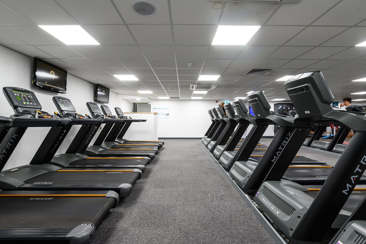PureGym Burnham: Rows of treadmills and other cardio machines in a well-lit fitness centre.
