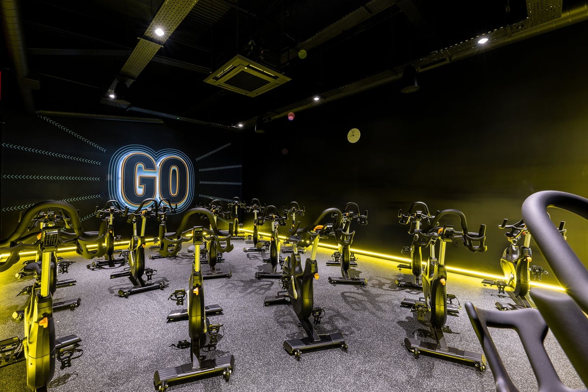PureGym Liverpool Edge Lane: Rows of stationary bikes in a dimly lit studio with neon Go signage.
