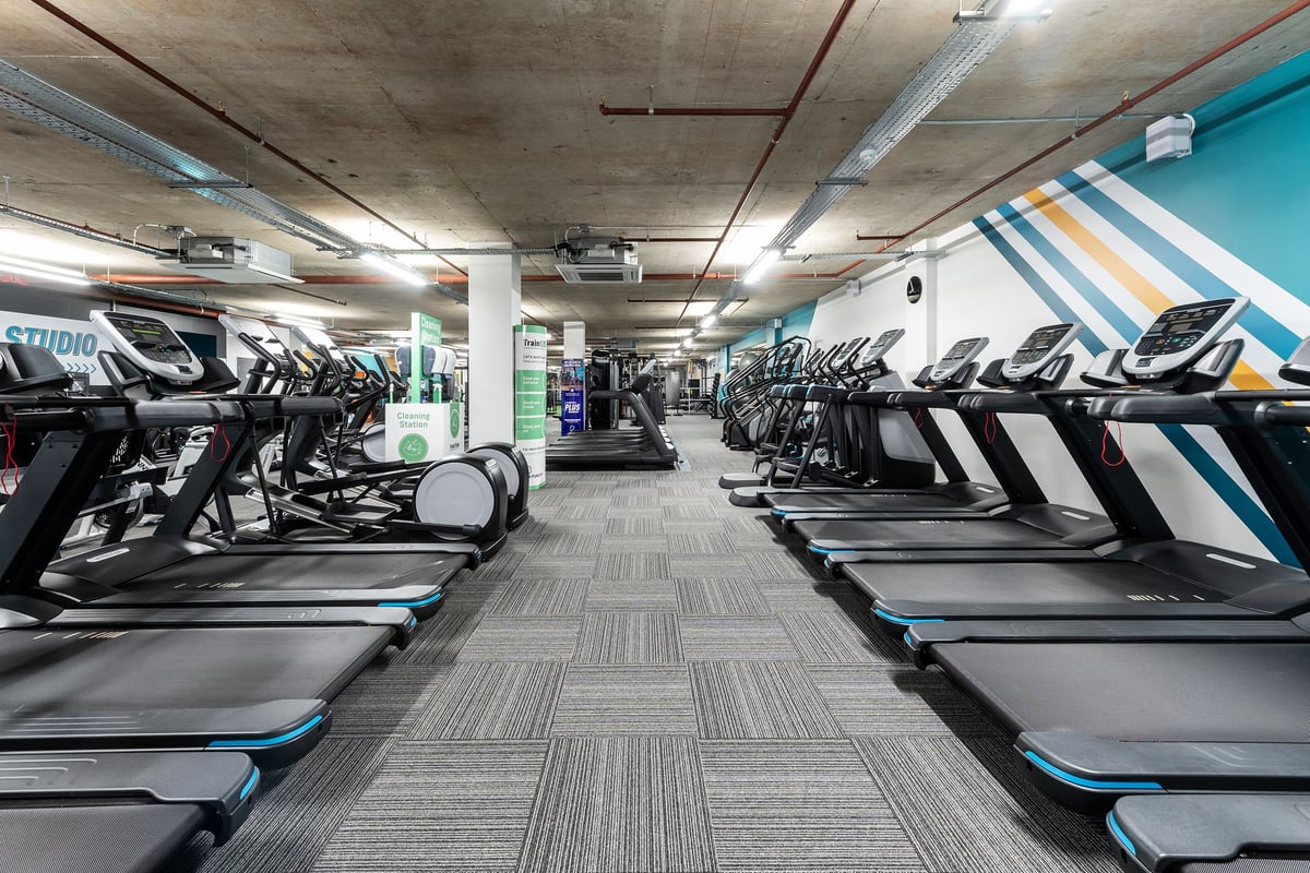 PureGym London Angel: Rows of treadmills, ellipticals and other cardio machines in a dimly lit gym.