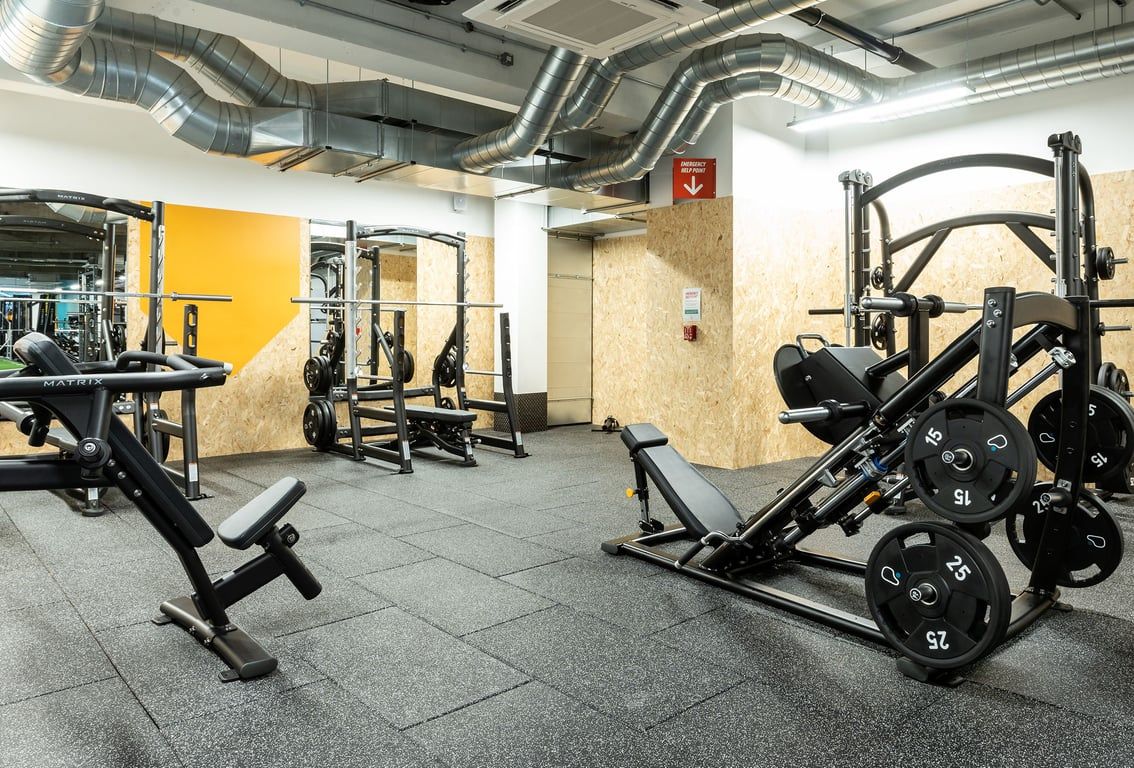PureGym London Streatham: Weight benches, squat racks, free weights, and exposed ductwork in a gym setting.