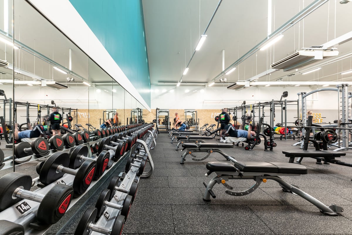 PureGym Bangor Northern Ireland: Weight benches, free weights, and mirrored walls in a large gym space.