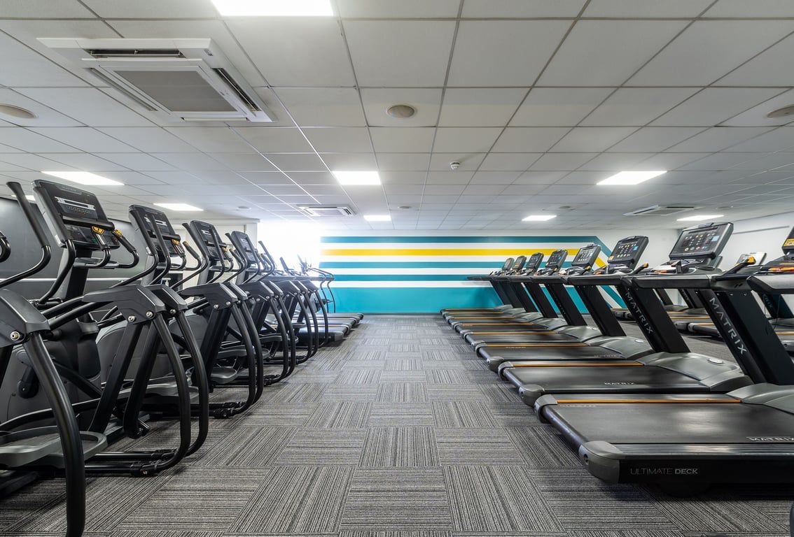 PureGym Sutton Coldfield: Rows of treadmills facing a mirrored wall in a brightly lit gym space.