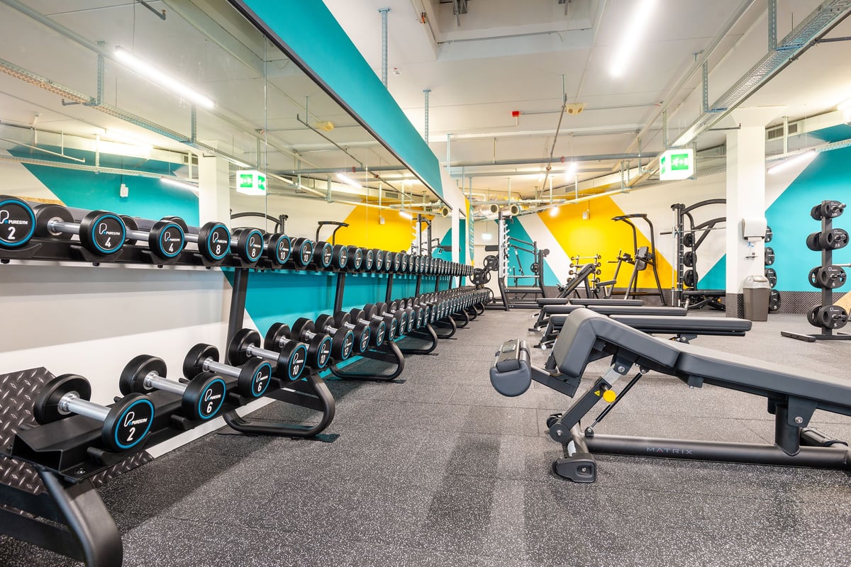 PureGym Wil: Des rangées de vélos d'exercice, des haltères, des bancs et une zone gazonnée.