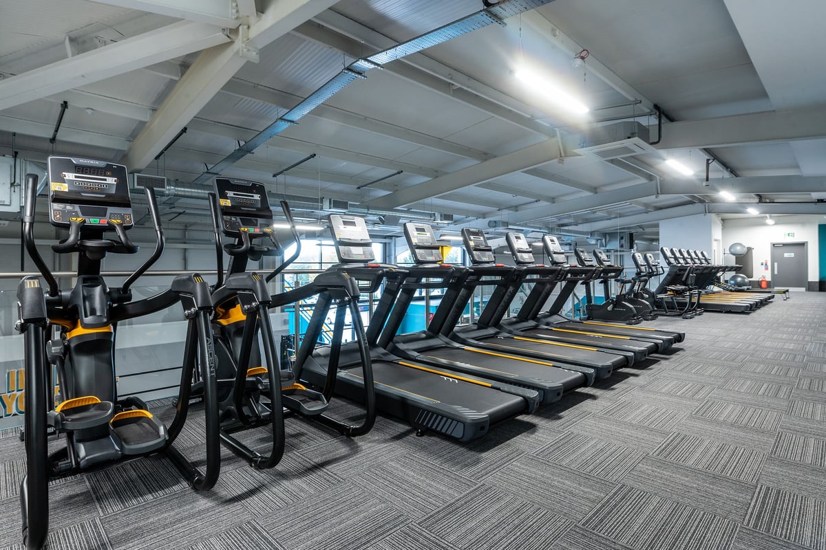 PureGym Trowbridge: Rows of treadmills, dimly lit interior space with exposed ceiling beams.