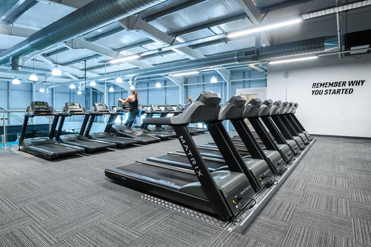 PureGym Lichfield: Rows of treadmills and motivational wall text in a modern gym setting.
