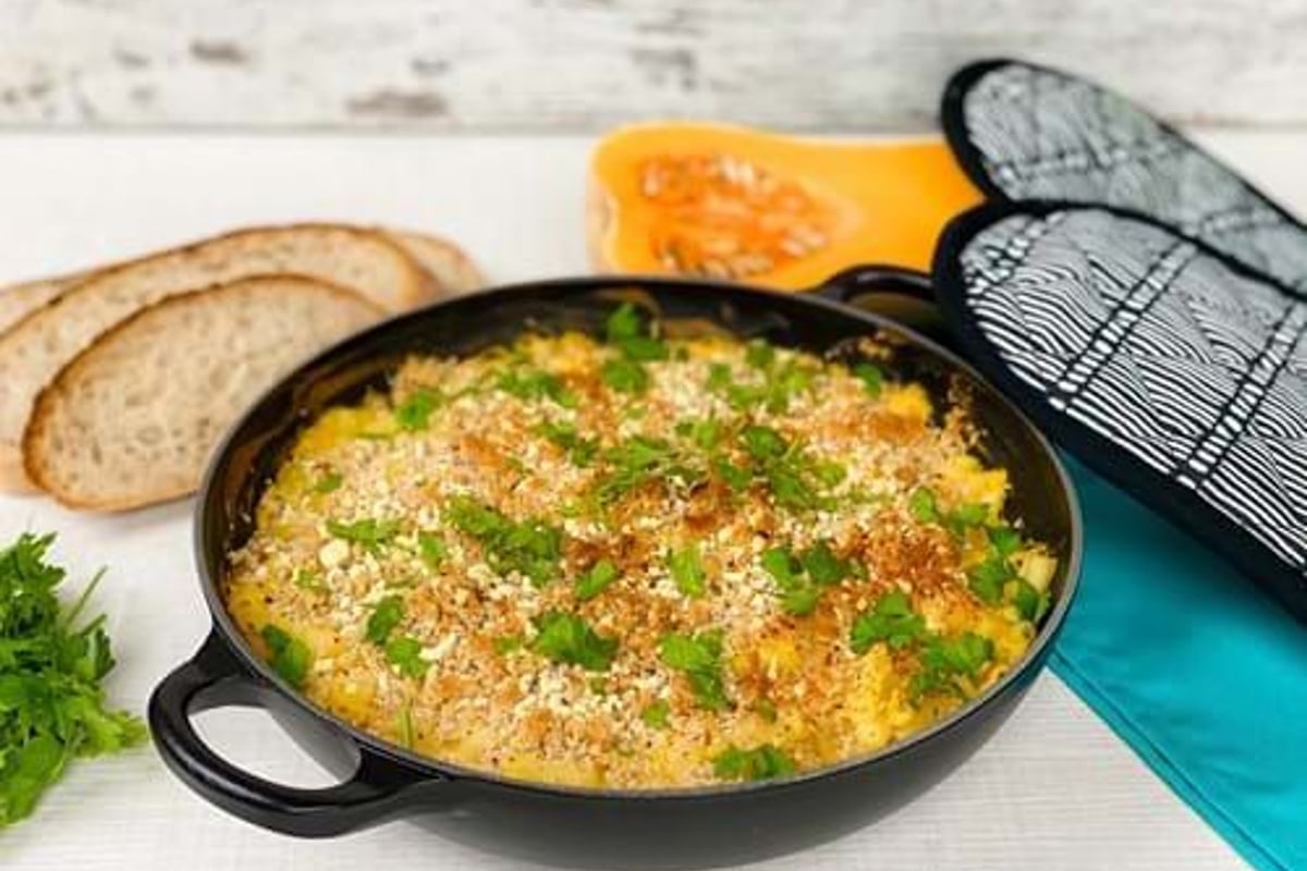 Baked macaroni and cheese topped with breadcrumbs and parsley in a black pan