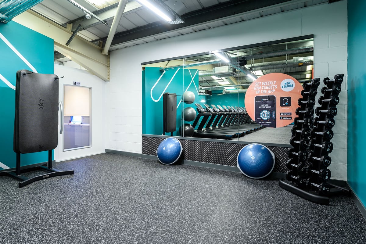 PureGym Burgess Hill: Resistance machines, exercise balls, rubberized flooring in a teal and grey fitness studio.