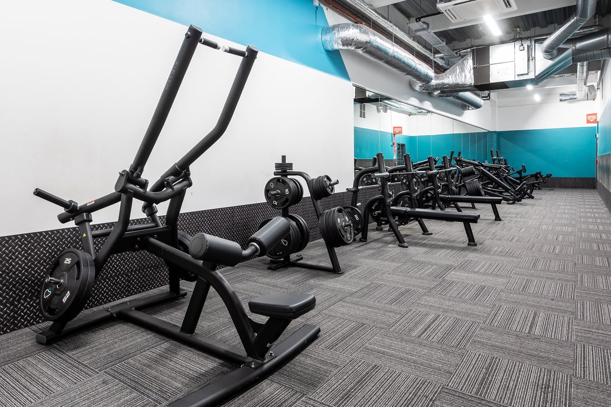 PureGym York: Rows of weight benches, resistance machines, and rubberized flooring in a fitness studio.