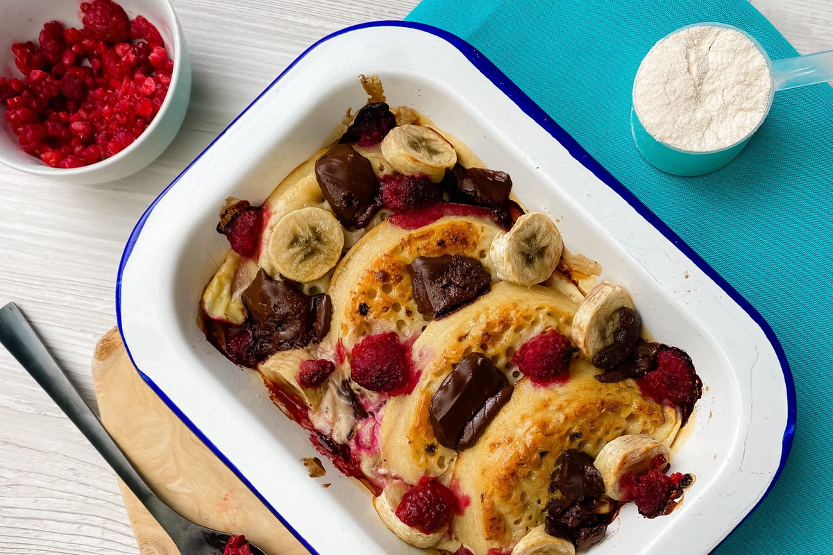 Baked crumpets topped with banana slices, berries and salted caramel in white dish
