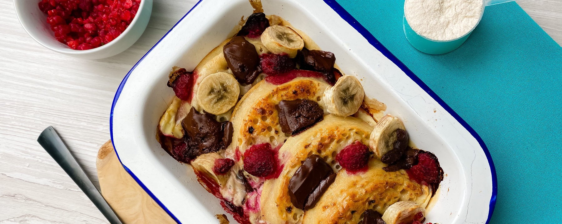 Baked crumpets topped with banana slices, berries and salted caramel in white dish