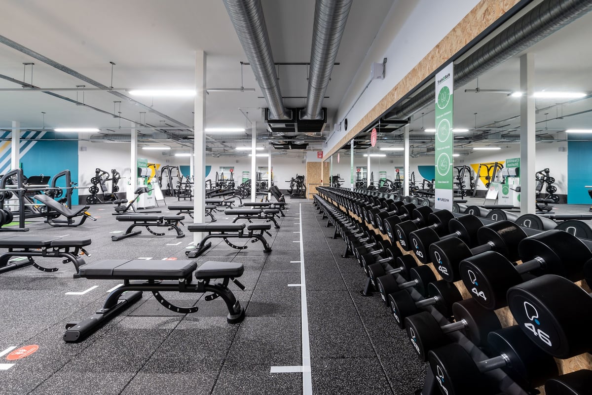 PureGym Bournemouth Mallard Road Retail Park: Weight benches, dumbbells, mirrors, and industrial ceiling in the gym.