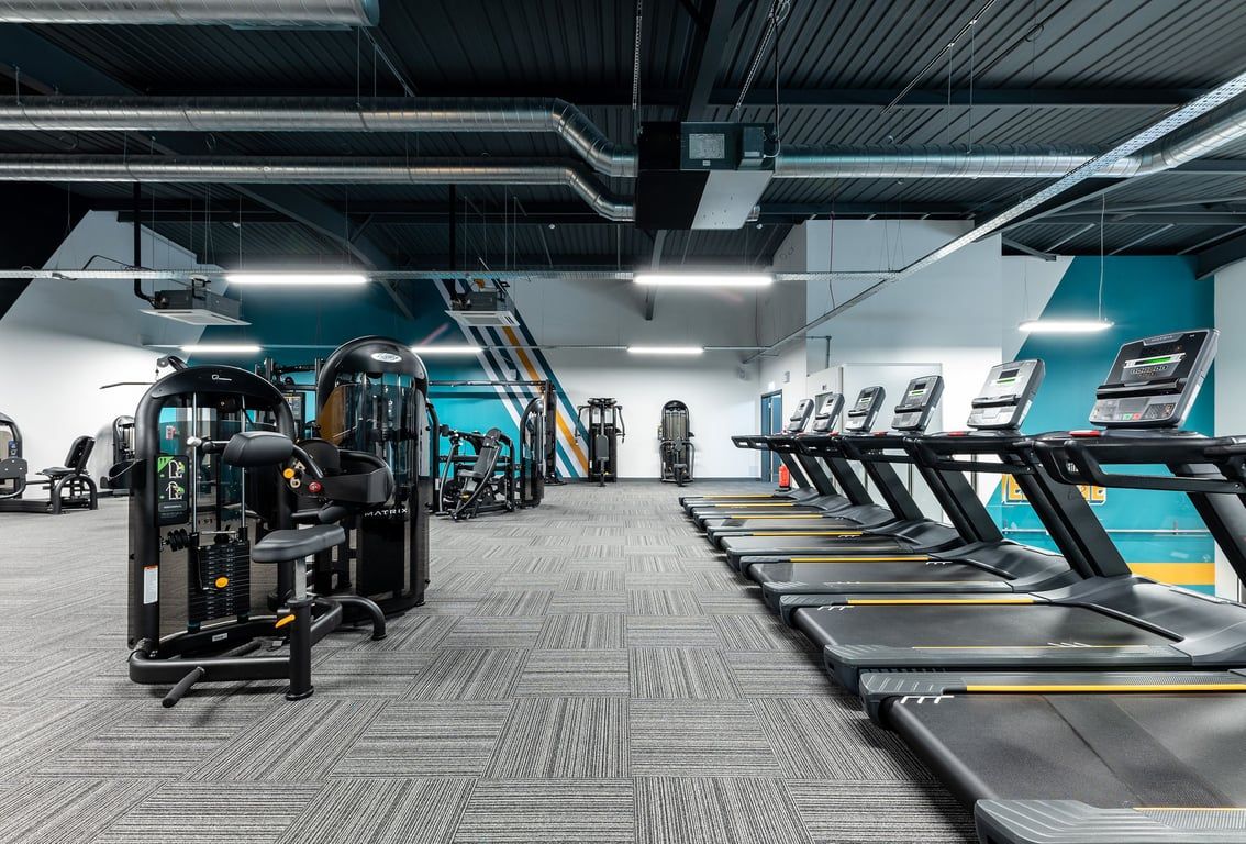 PureGym Sevenoaks: Rows of futuristic-looking treadmills, weight machines in vibrant teal and grey colour scheme.