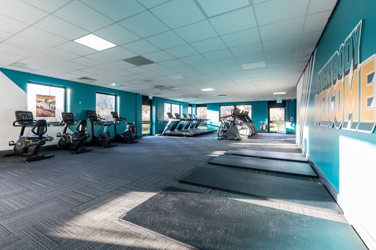 PureGym Livingston: Rows of treadmills, weight machines, exercise bikes in a teal-coloured fitness studio.