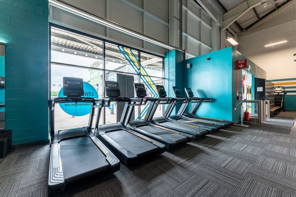 PureGym Durham City Retail Park: Rows of treadmills and exercise bikes in a vibrant turquoise fitness studio.