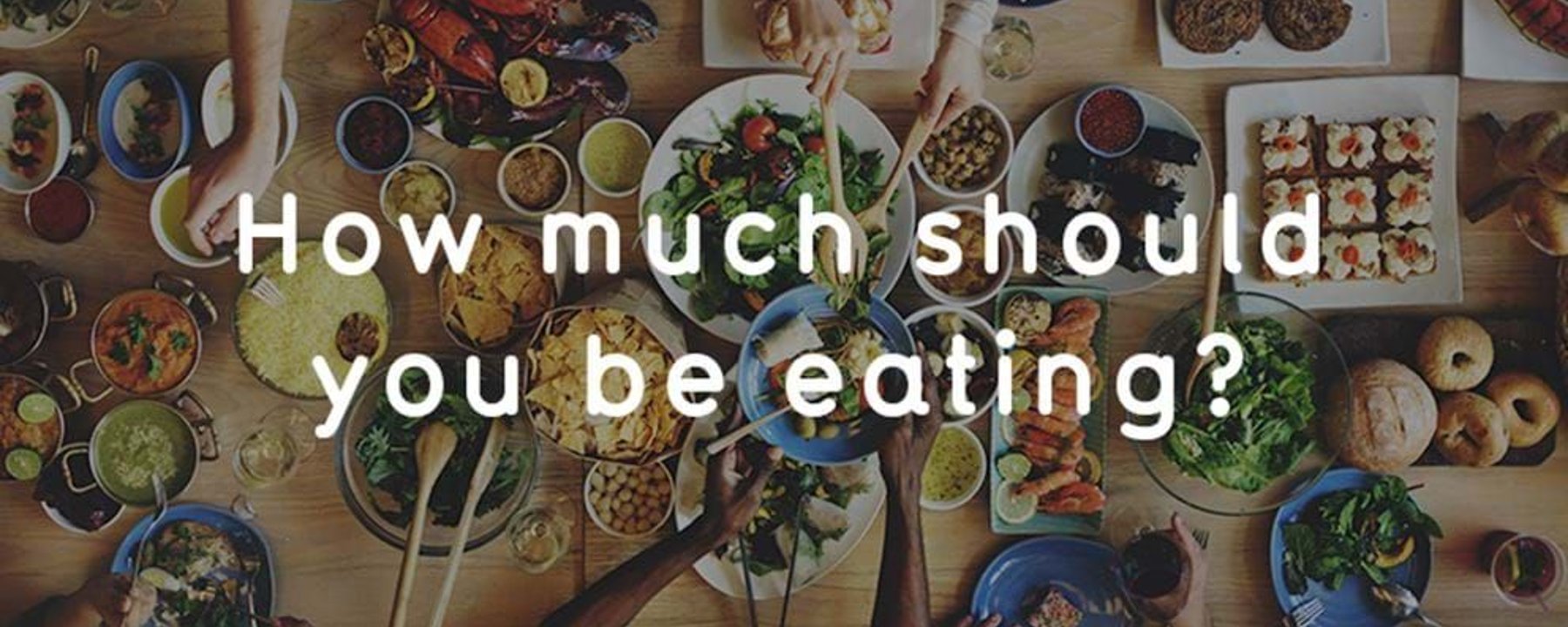 People sharing a large meal with various dishes including salad, bread, and seafood on a w