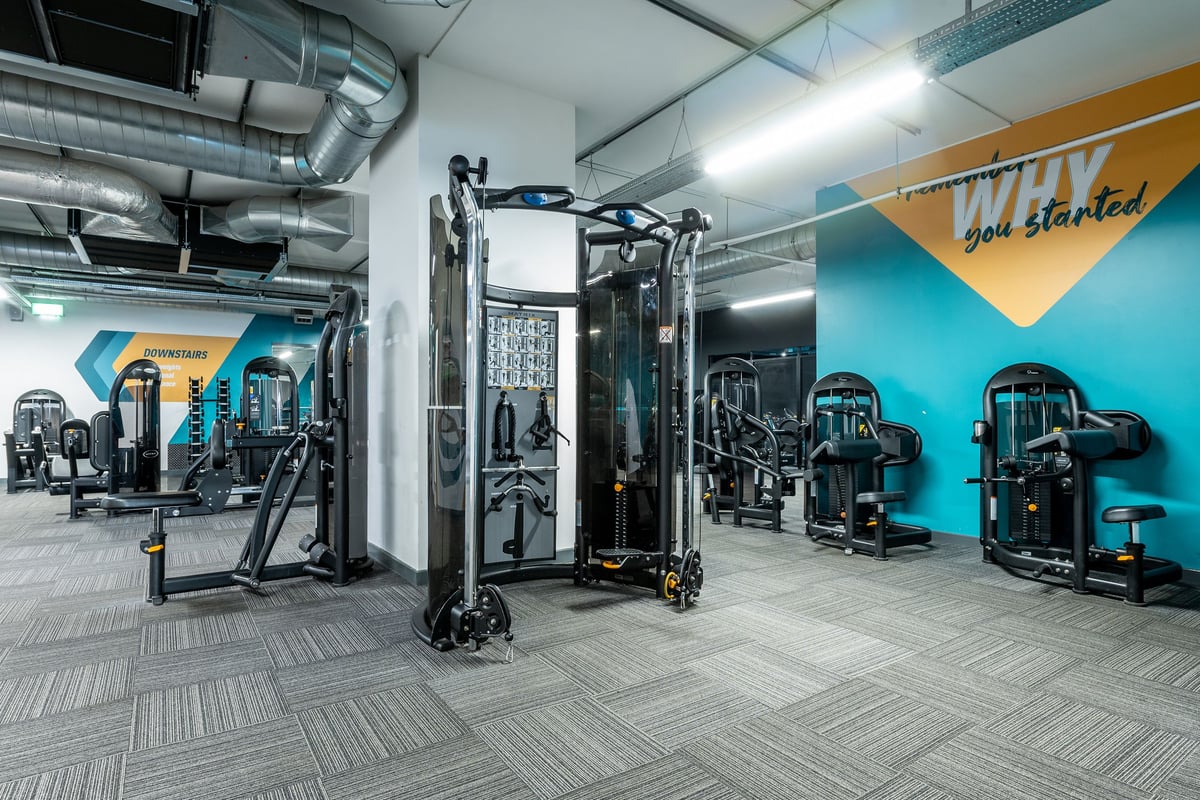 PureGym Stevenage: Resistance training area with cable machines, weight racks, benches, and rubberized flooring.