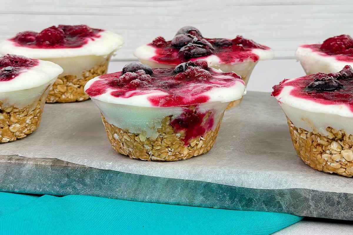 Frozen yoghurt cups with berry topping and oat bases on a turquoise exercise mat