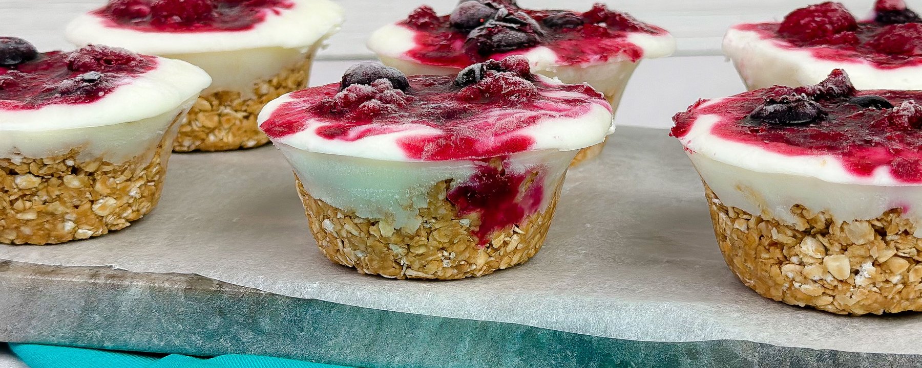 Frozen yoghurt cups with berry topping and oat bases on a turquoise exercise mat