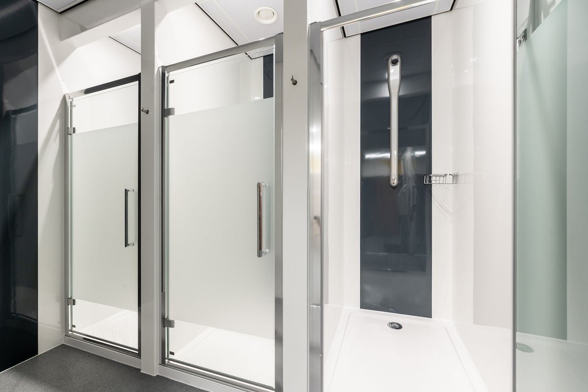 PureGym Derby Meteor Centre: Glass shower cubicles, metallic frames, tiled floor - changing rooms.
