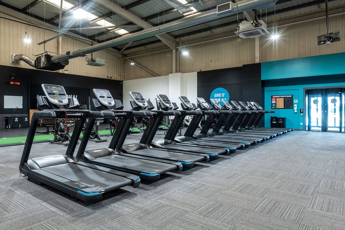 PureGym Weston-super-mare: Rows of treadmills in a large gym space with fans and teal accent walls.