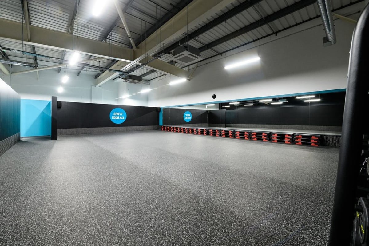 PureGym Cardiff Bay: Rows of speed bags, rubberized flooring, and mirrored walls in a fitness studio.
