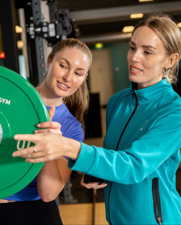 PureGym instructor helping a member with a barbell