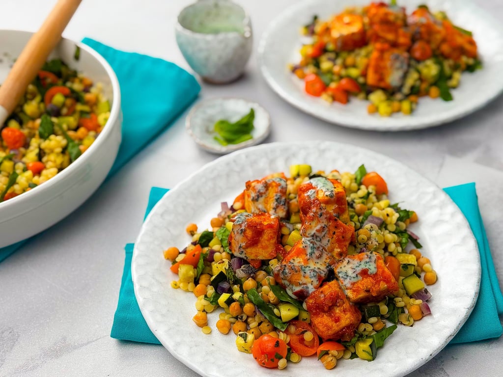Grilled paneer cubes with mixed vegetable salad and creamy herb dressing on white plates