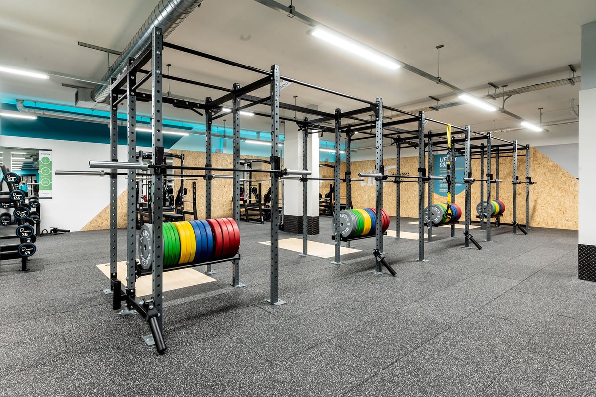PureGym Milton Keynes Kingston Centre: Row of power racks, weight plates, bars, and rubberized flooring in a gym studio.