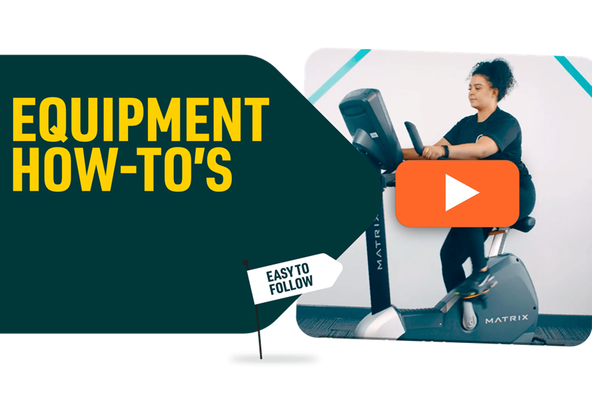 Woman using a stationary exercise bike with a play button overlay on the screen