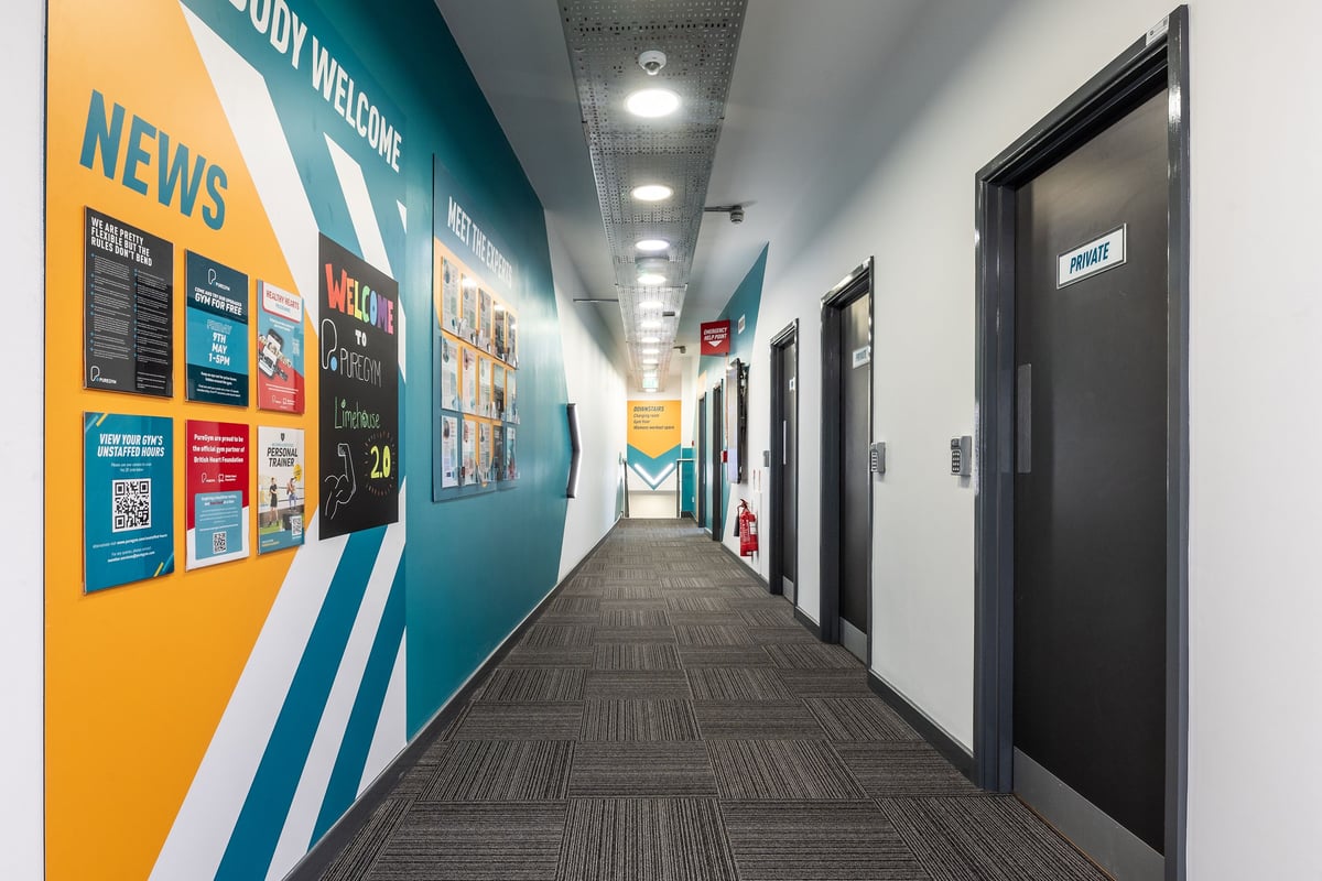PureGym London Limehouse: Gym corridor with news posting and welcome signage.