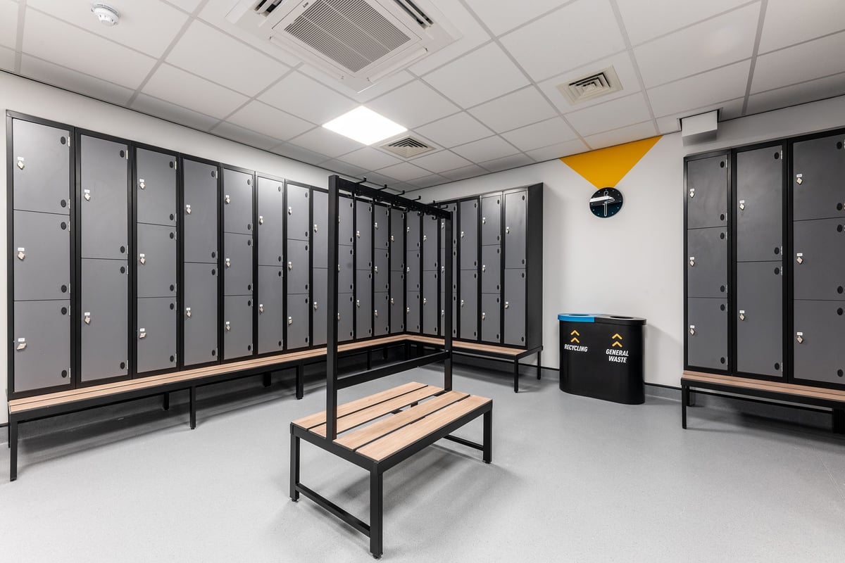 PureGym Coleraine: Rows of lockers, benches, and recycling bins in a changing room area.