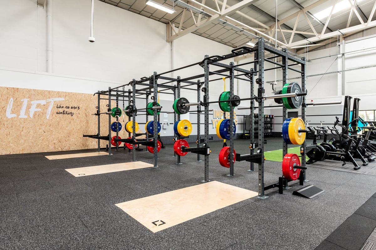 PureGym Bridgend: Racks with weight plates in various colours, rubberized floors, and motivational wall art.