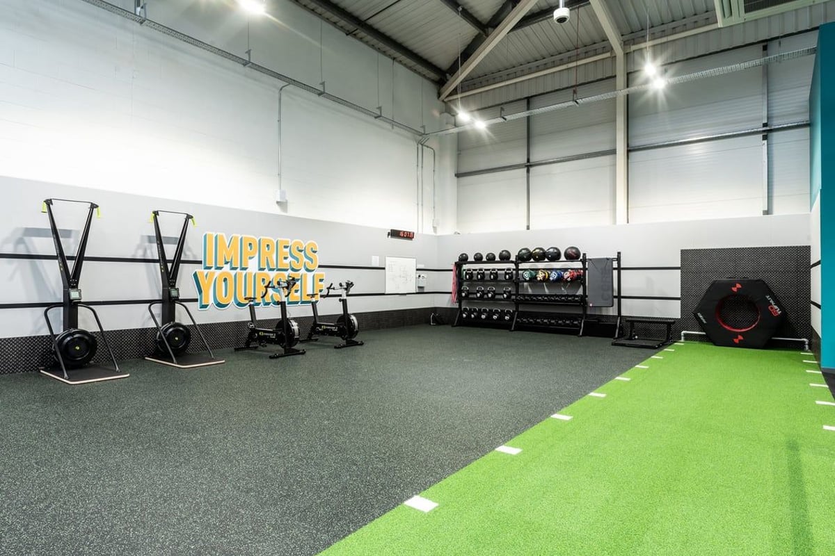 PureGym Newbury: Resistance sleds, racks for weightlifting, dumbbell and barbell weight racks, green turf area.