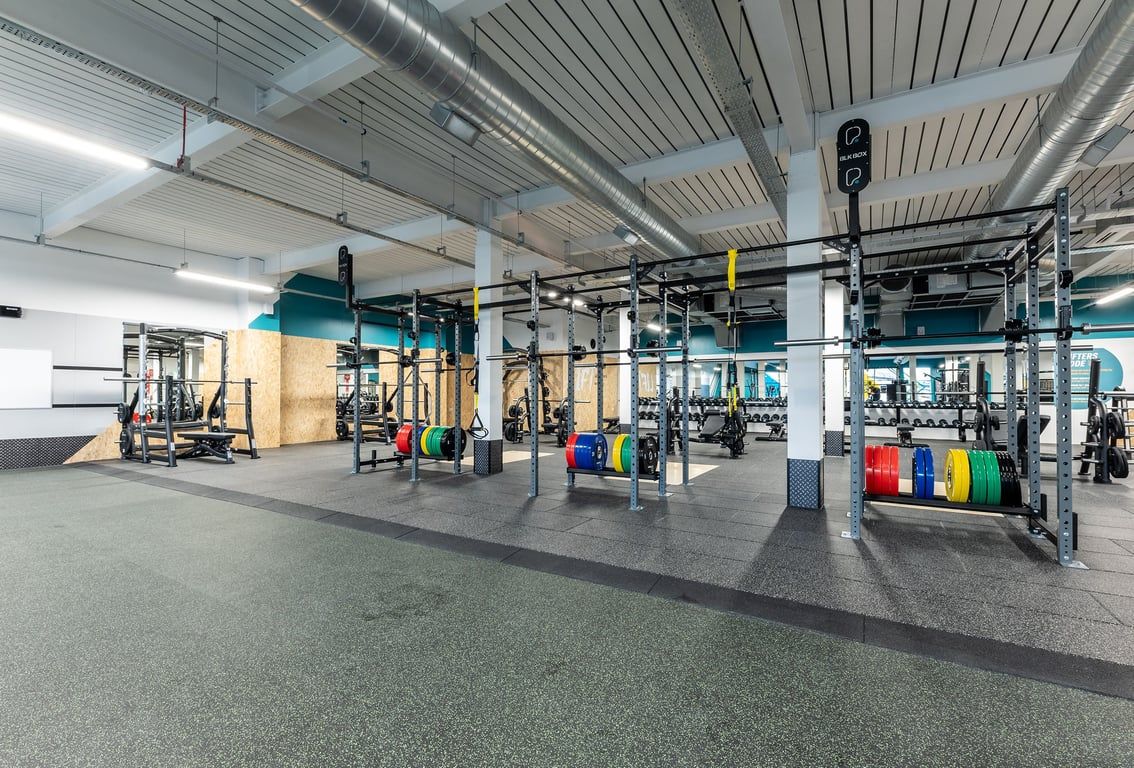 PureGym Glasgow Milngavie: Racks, benches, free weights, rubberized flooring in a spacious gym setup.