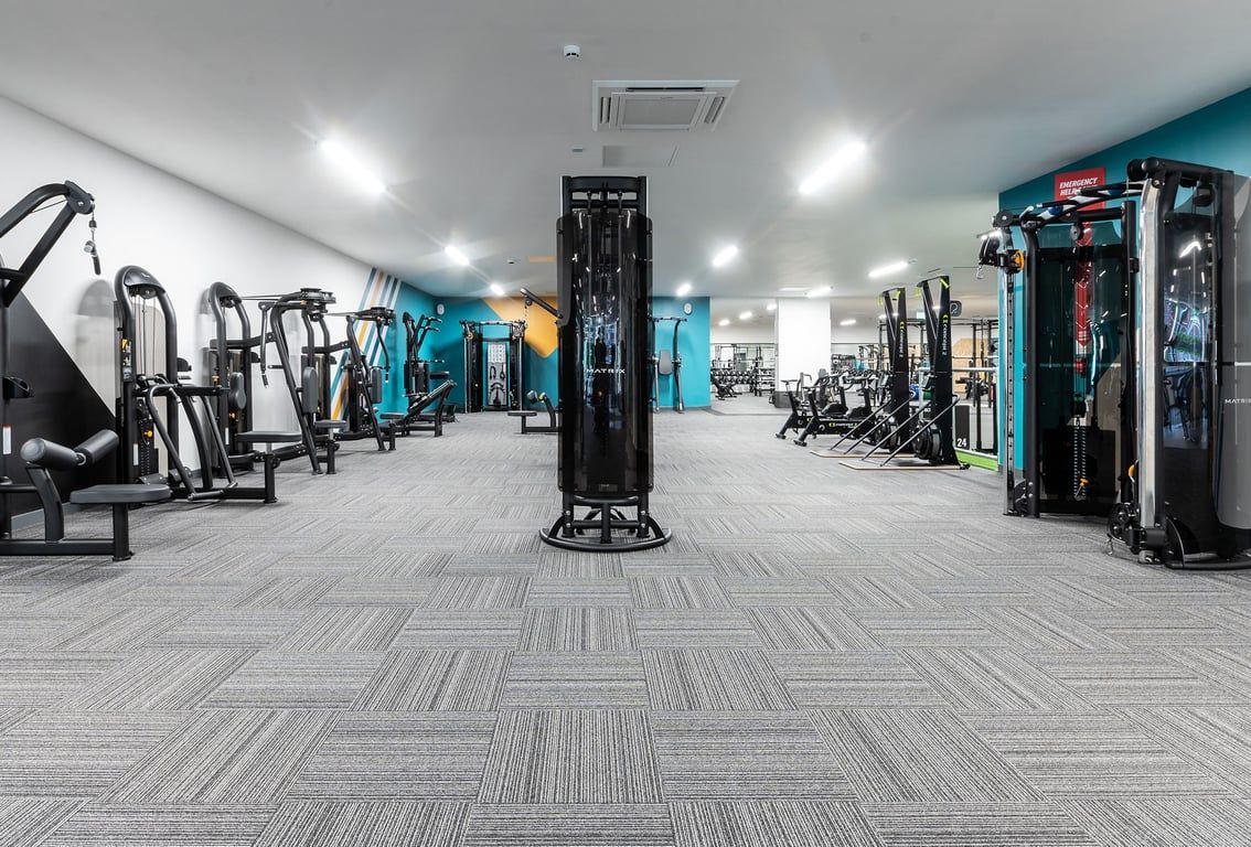 PureGym Tyldesley: Weight machines, cable crossovers, resistance bands, benches, rubberized floors in a modern gym interior.