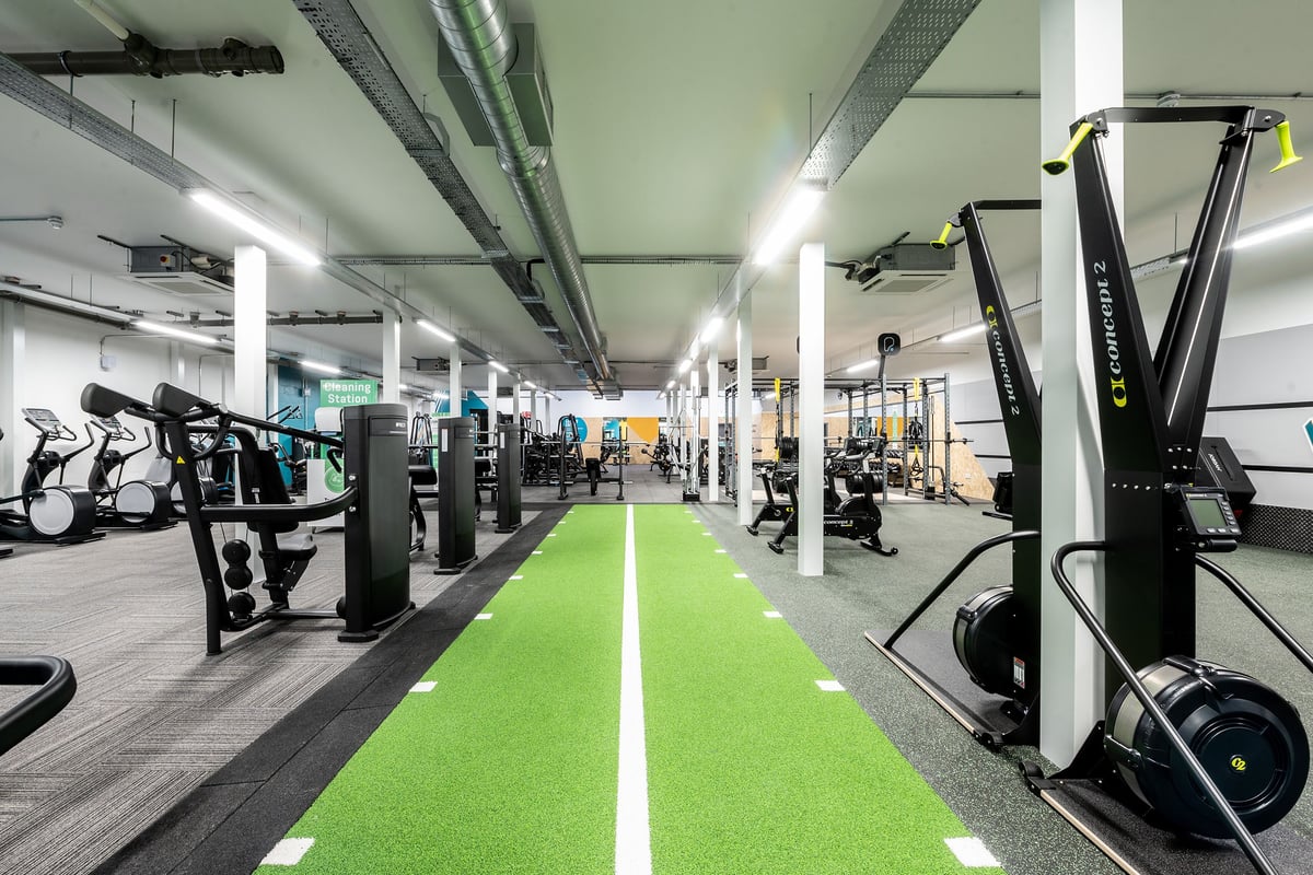 PureGym Inverness Inshes Retail Park: Rows of resistance machines, smith machines, cardio equipment on a green turf floor.