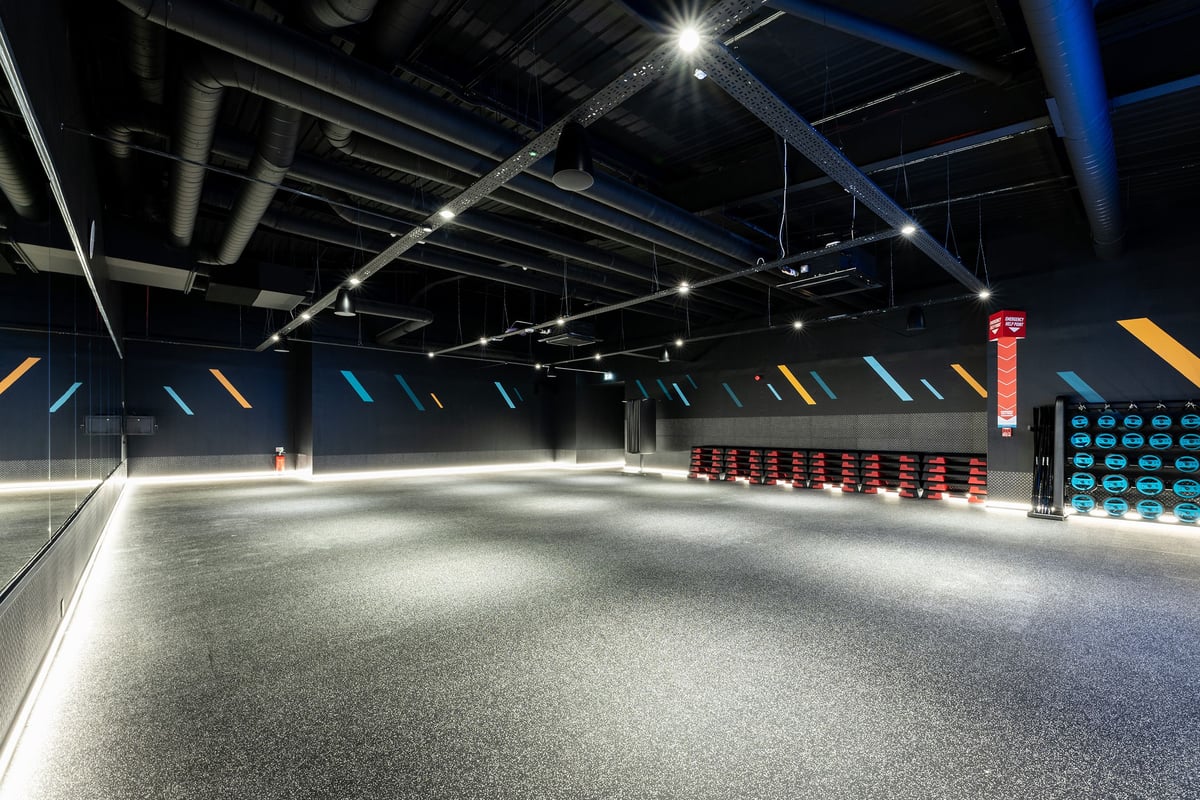 PureGym Sevenoaks: Rows of freeweights, weightlifting platforms, and mirrored walls in a darkly lit studio.