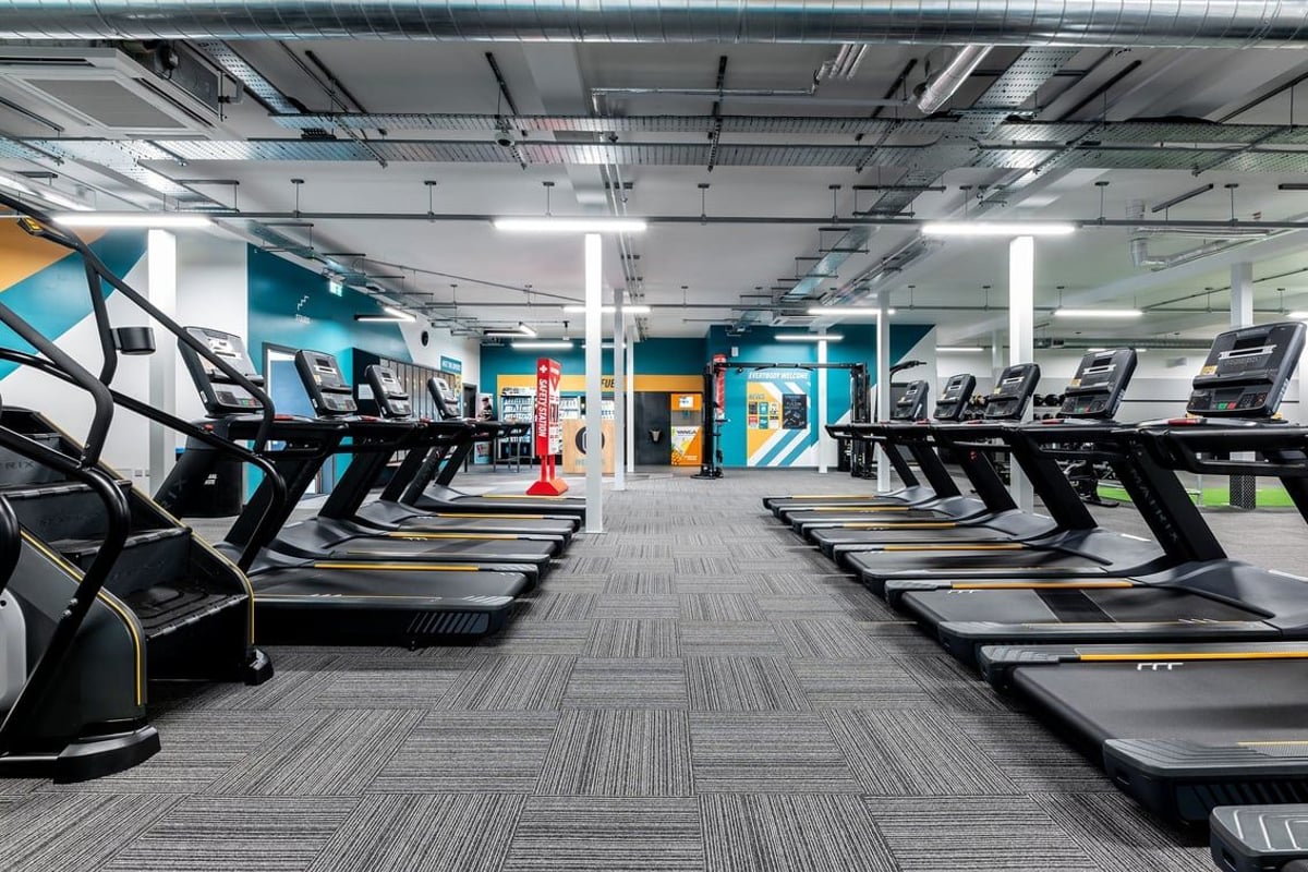 PureGym Shrewsbury Meole Brace: Rows of modern treadmills and cardio equipment in a bright, colorfully accented gym interior.
