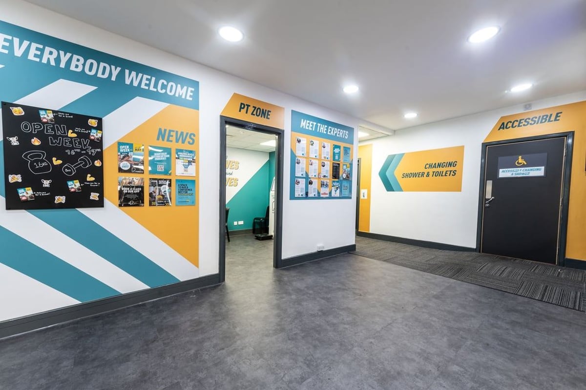 PureGym Woking: Signage, entryways, and waiting area with entry paths into areas of the gym.