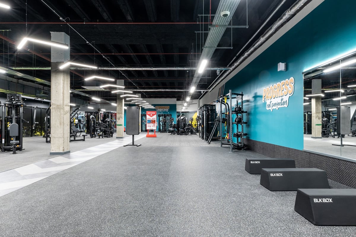 PureGym London Stratford: Weightlifting area with resistance machines, benches, free weights, and turf flooring.